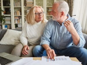Elderly couple reviewing documents at home while discussing ndis aged care funding options and support services.